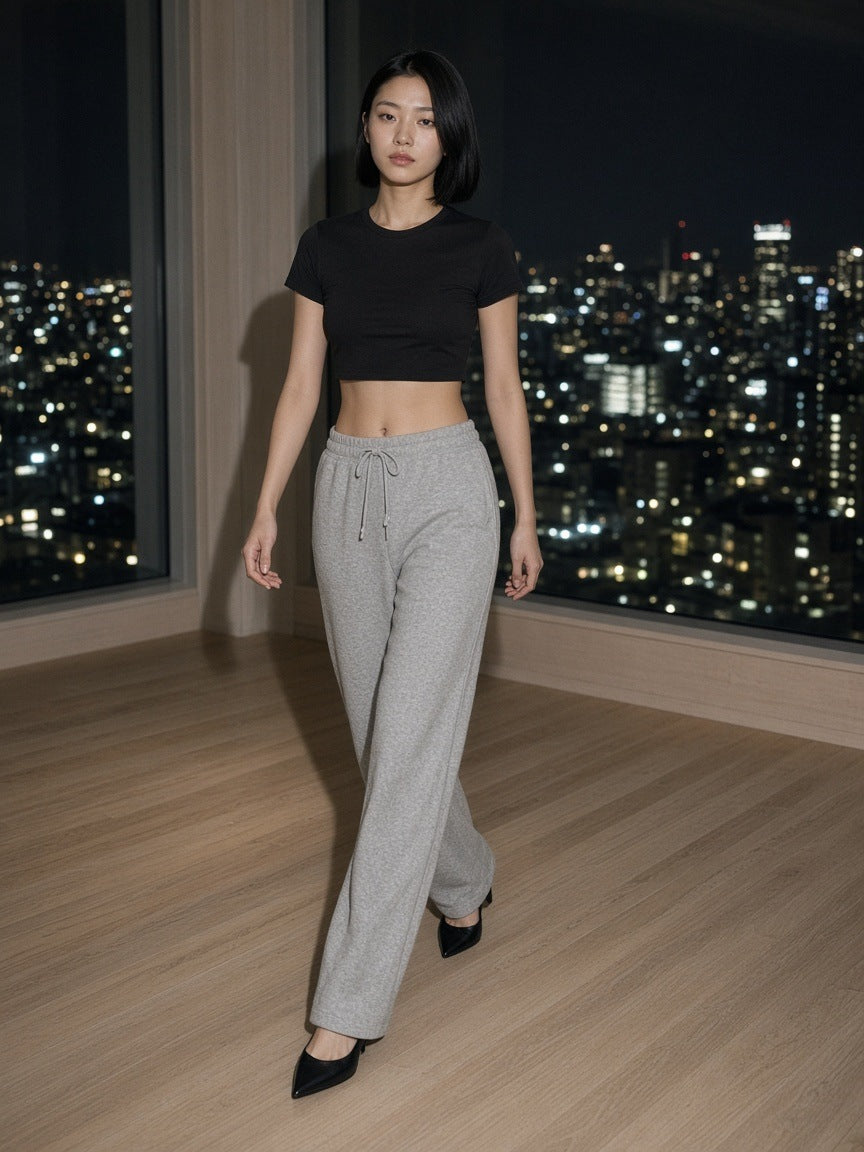 Woman in the Essential Drawstring Straight-Leg Sweatpants in Flower Gray walking through a hotel suite above Tokyo at night