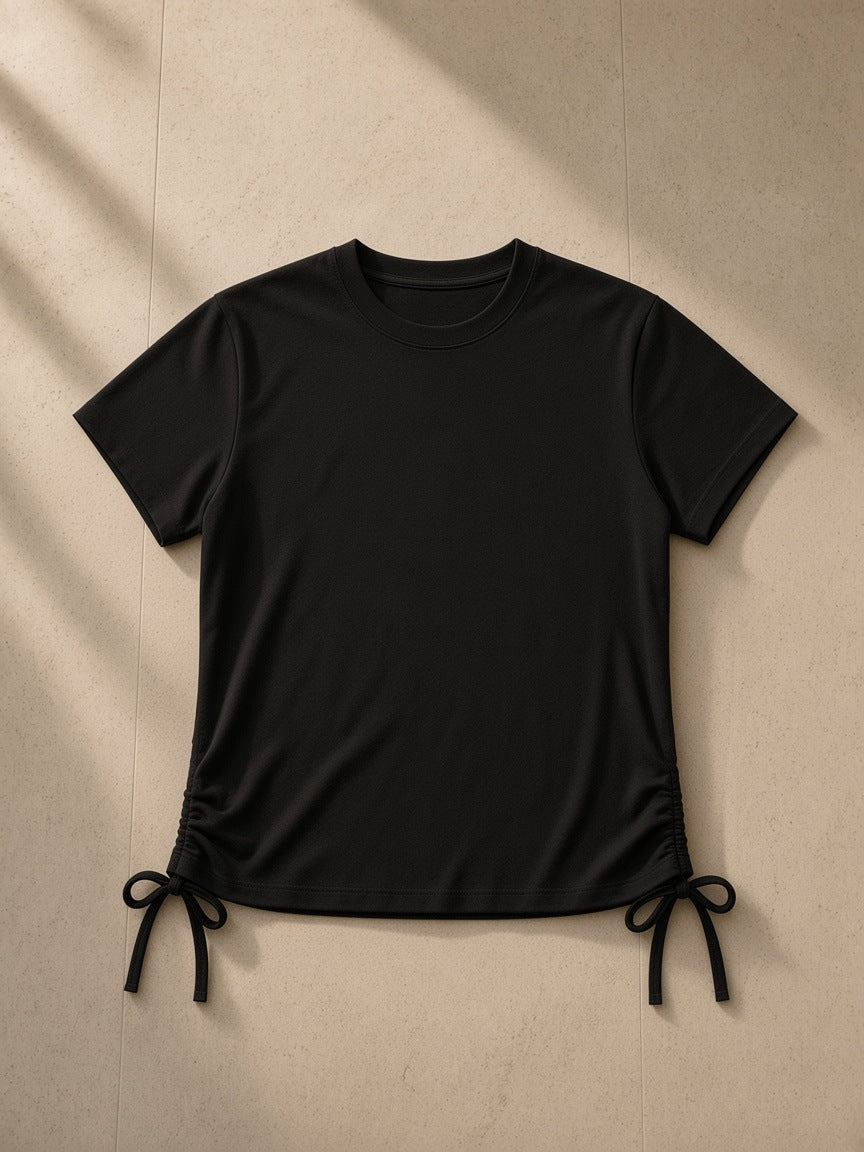 Essential Drawstring T-Shirt in Black, laid flat on pale limestone