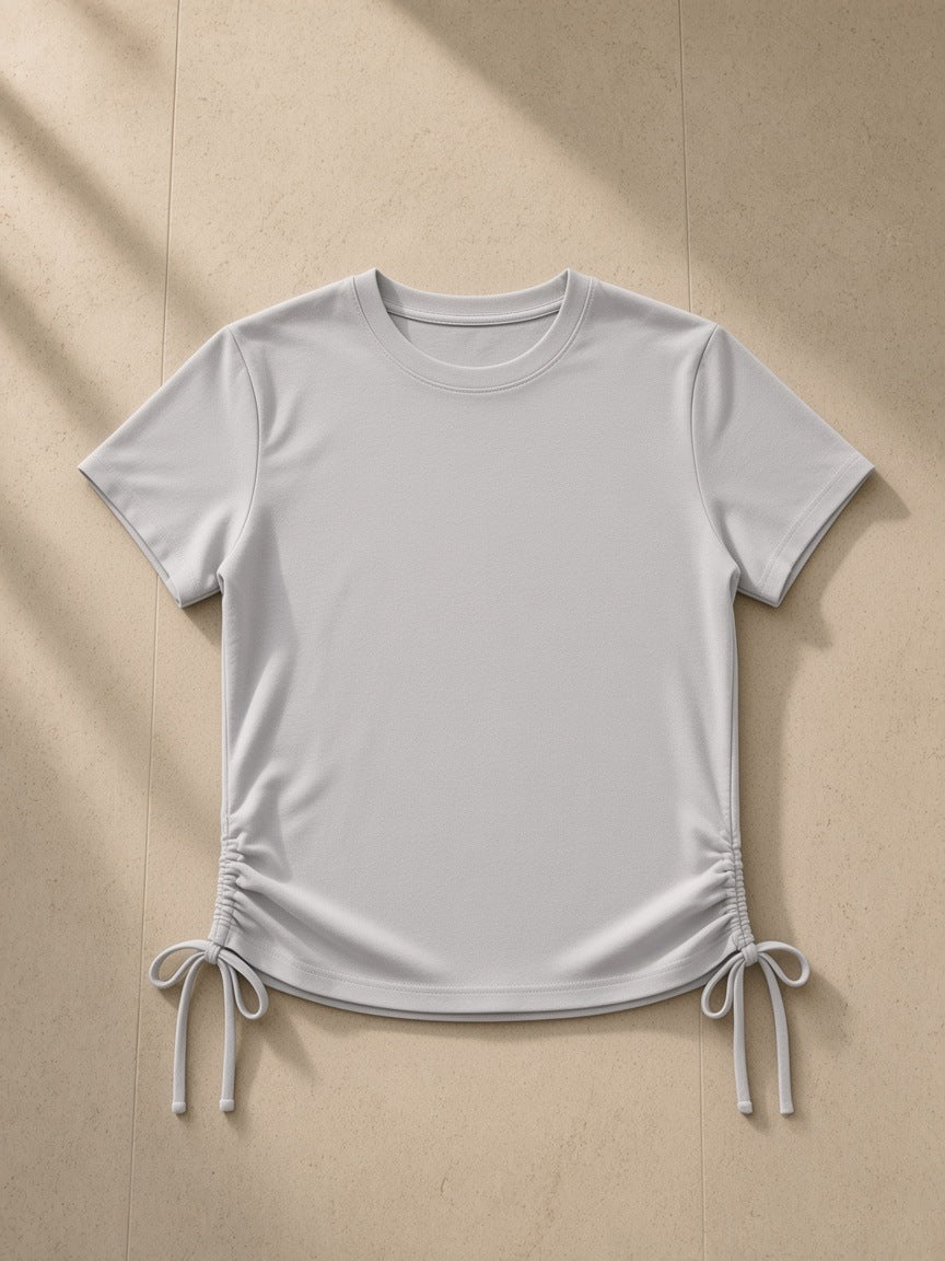 Essential Drawstring T-Shirt in Light Gray, laid flat on pale limestone