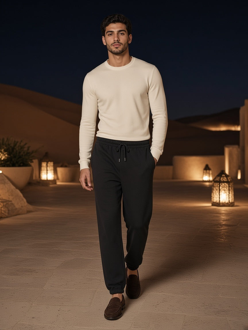 Man in Essential Fleece Sweatpants in Black in a desert resort courtyard outside Dubai at night