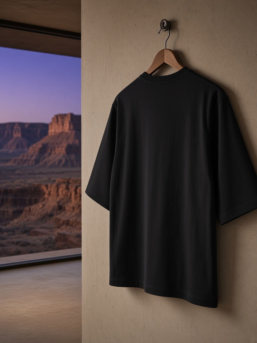 Essential Half Sleeve Ribbed T-Shirt in Black on a wooden hanger hooked on a pale plaster wardrobe in a Utah desert suite at night