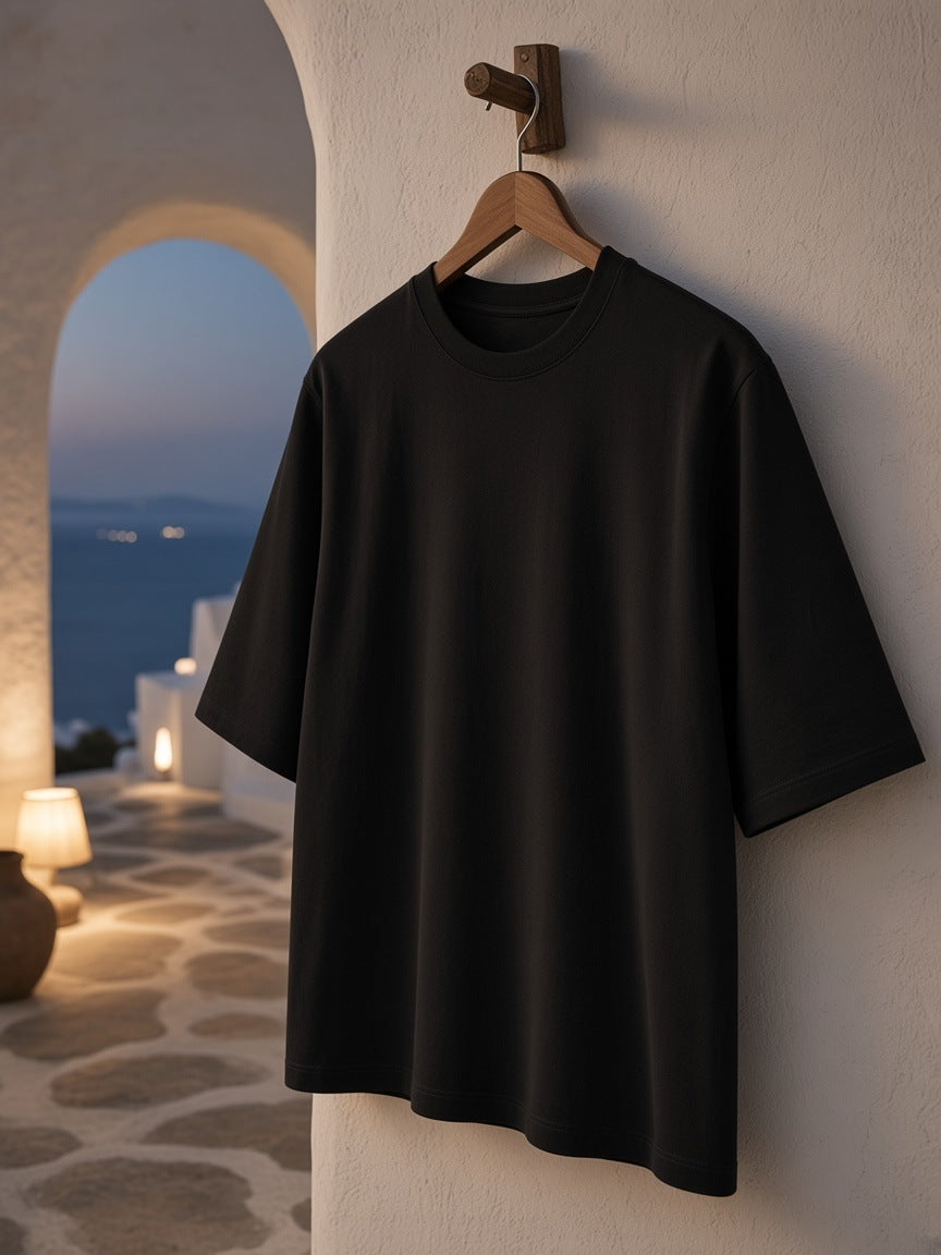 Essential Half Sleeve Ribbed T-Shirt in Black hanging from a wooden peg on a whitewashed wall in a Mykonos terrace suite at night
