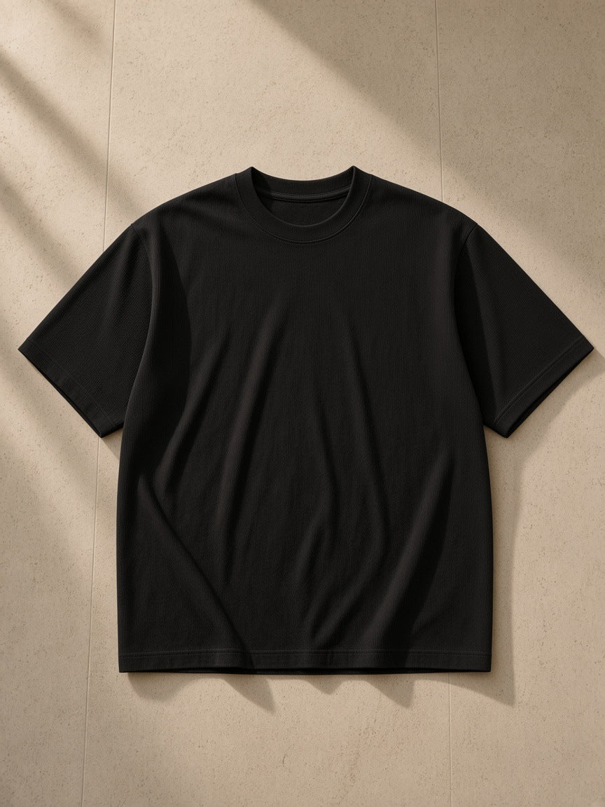 Essential Half Sleeve Ribbed T-Shirt in Black, laid flat on pale limestone