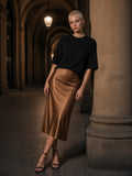 Woman in the Essential Half Sleeve Ribbed T-Shirt in Black and a satin midi skirt under the porticoes in Bologna at night