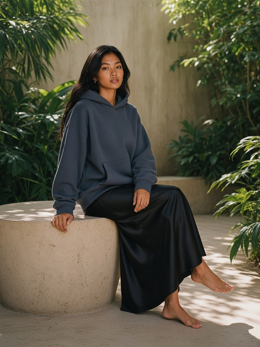 Woman in the Essential Heavyweight Boxy Fleece Hoodie in Gray Blue in a resort courtyard in the morning in Tulum