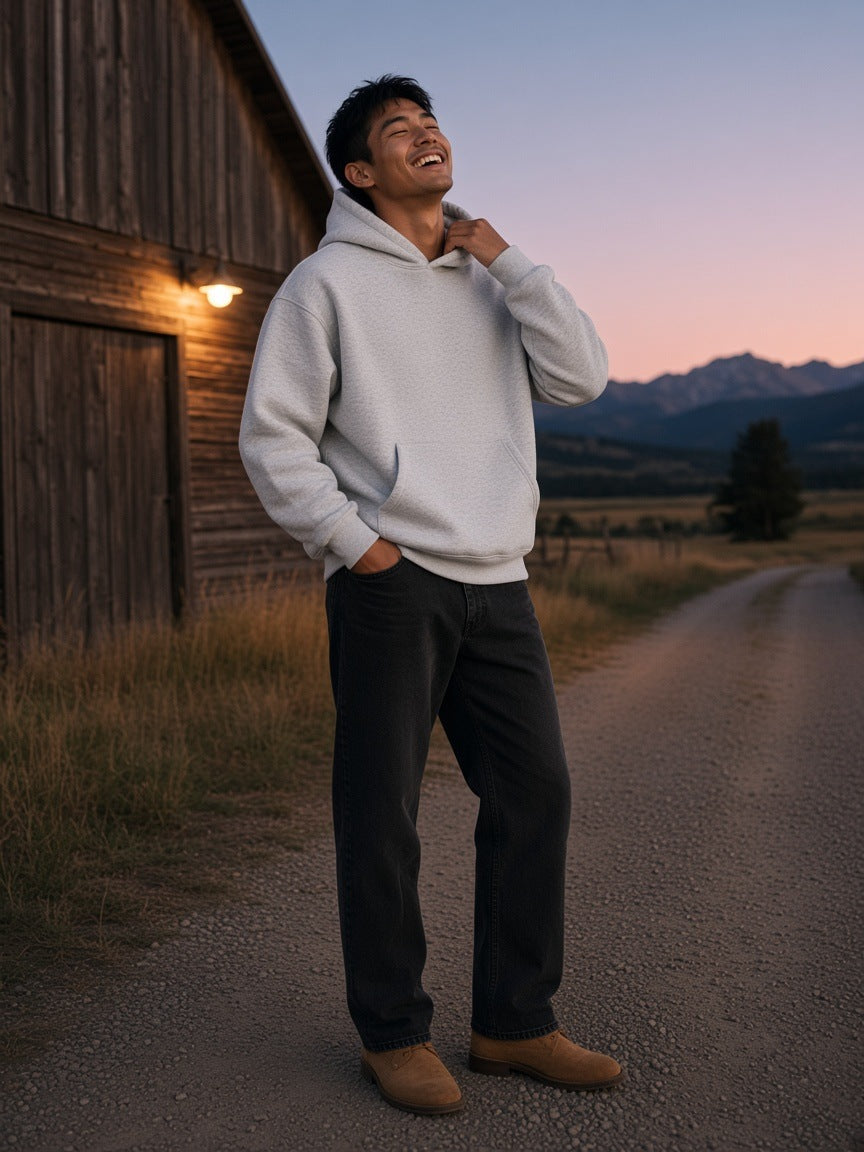 Man in the Essential Heavyweight Boxy Fleece Hoodie in Oat Gray leaning on the porch of a ranch lodge in Montana at night
