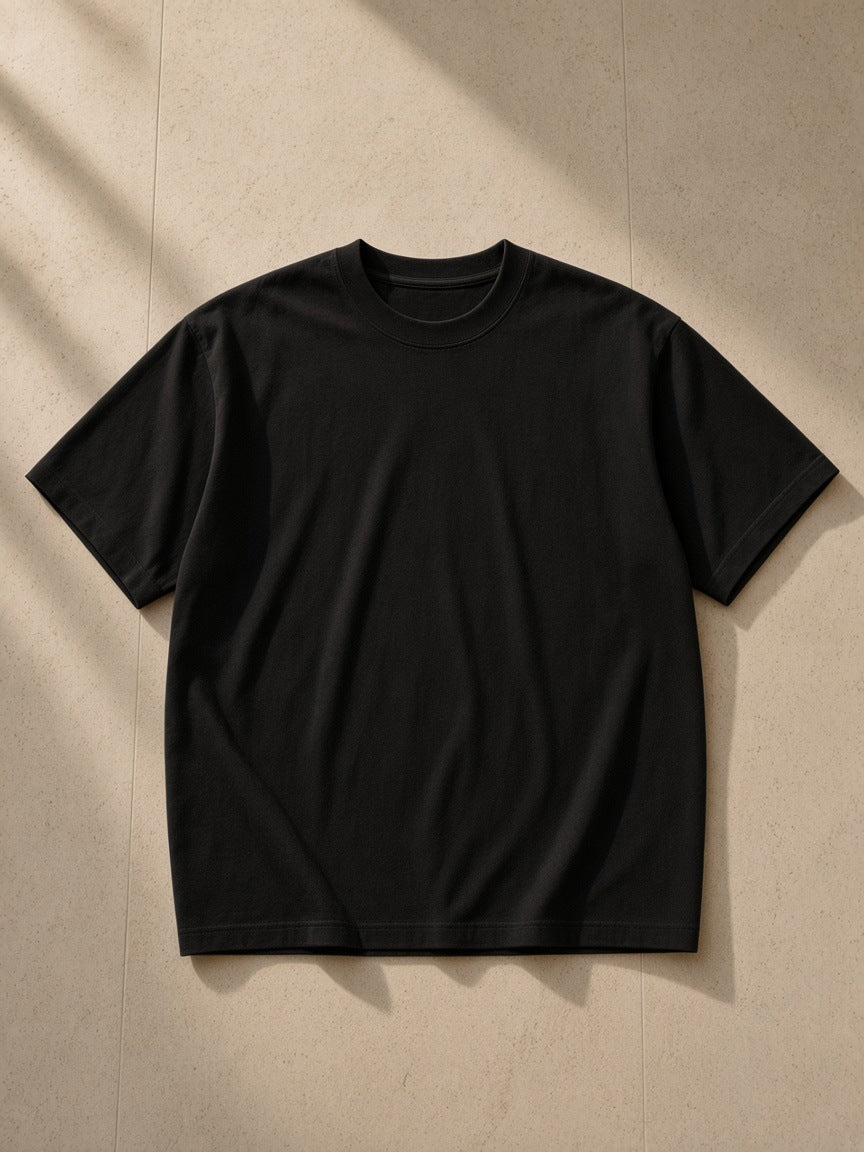 Women's Essential Heavyweight Cotton T-Shirt in Black, laid flat on pale limestone