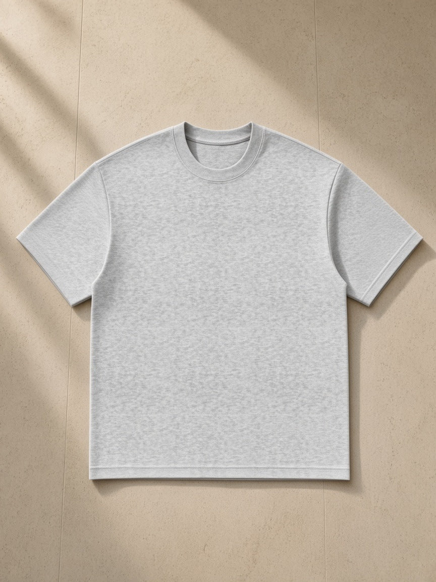 Essential Heavyweight Cotton T-Shirt in Heather Gray, laid flat on pale limestone