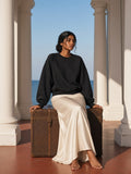 Woman in the Essential Heavyweight Dolman Sleeve Boxy Sweatshirt in Black in a colonial hotel colonnade in Galle in the morning