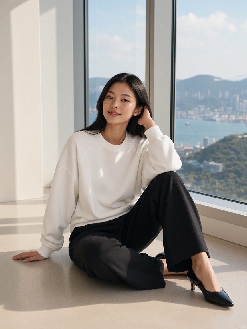 Woman in the Essential Heavyweight Dolman Sleeve Boxy Sweatshirt in White standing in a harbour penthouse in Hong Kong in the morning