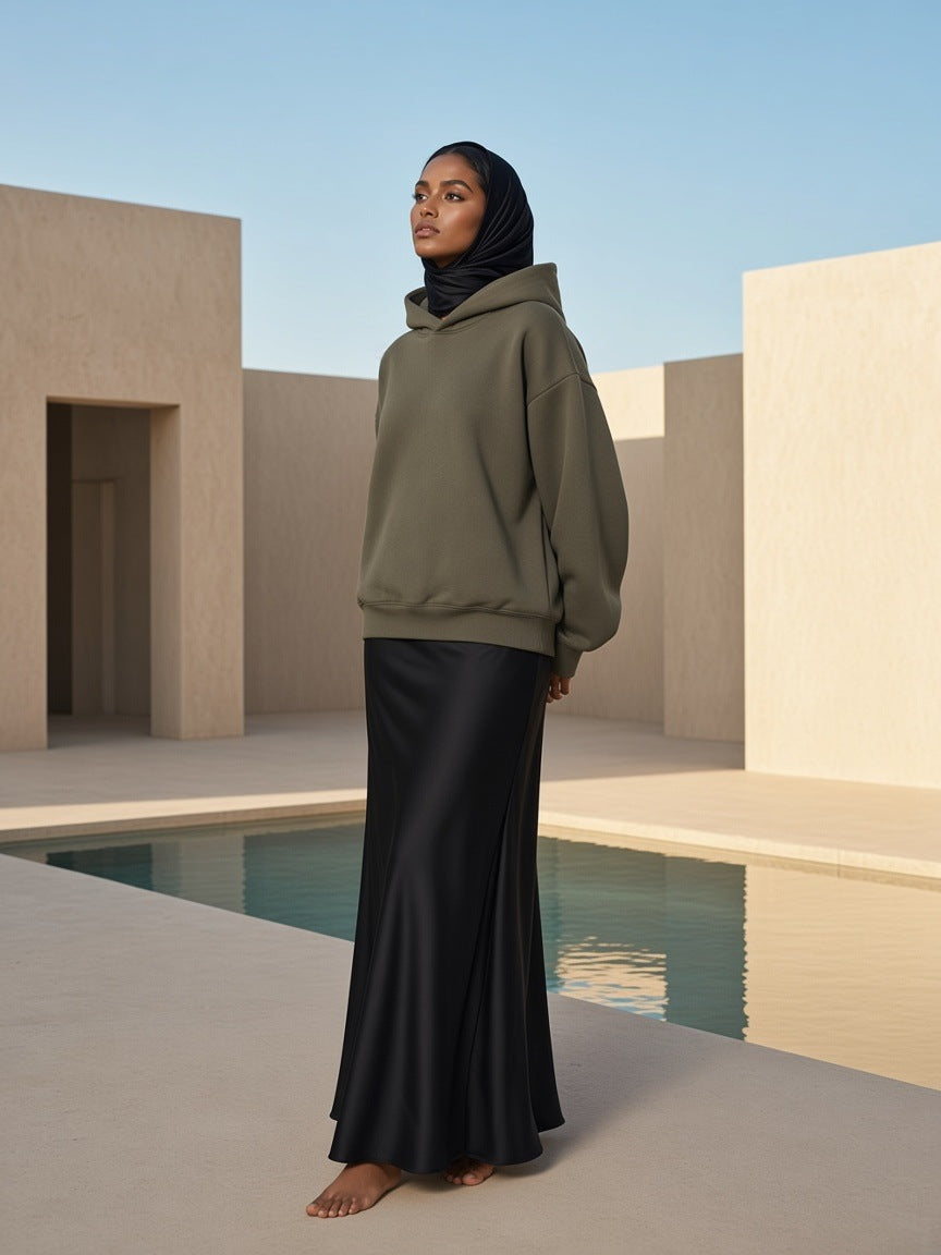 Woman in the Essential Heavyweight Fleece Hoodie in Olive Green in a desert resort courtyard in the morning near Muscat
