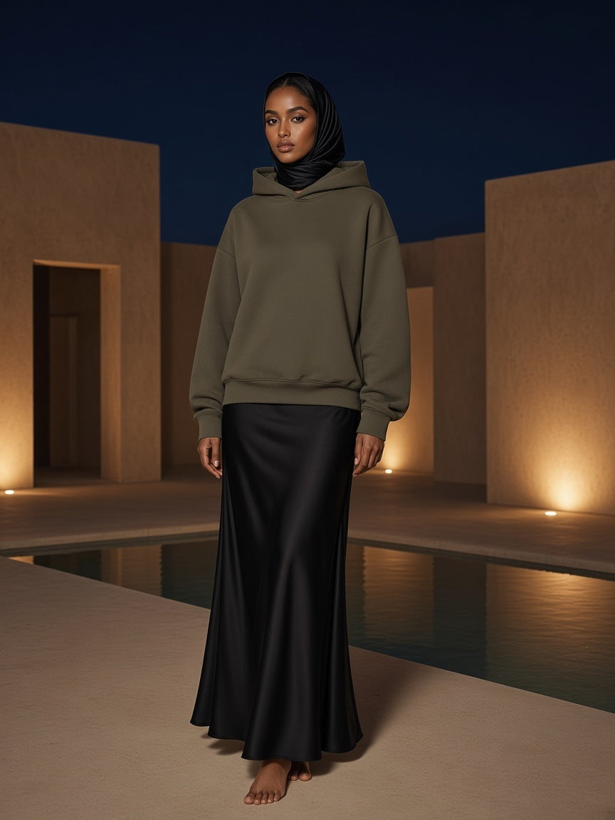 Woman in the Marcel Afters Essential Heavyweight Fleece Hoodie in Olive Green in a desert resort courtyard at night near Muscat