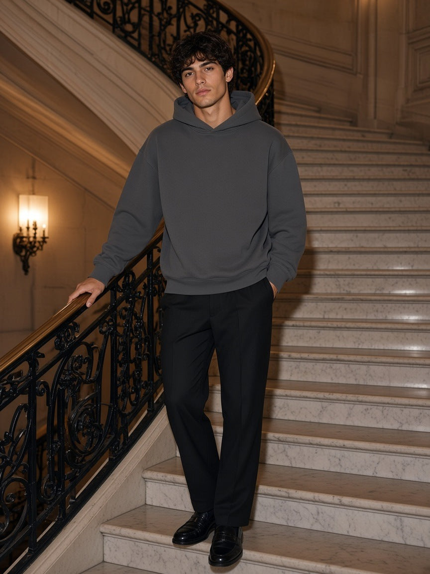 Man in the Marcel Afters Essential Heavyweight Fleece Hoodie in Charcoal Gray on a marble hotel staircase at night in Buenos Aires