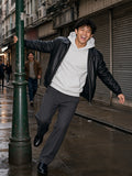 Man in the Essential Heavyweight Pocket Hoodie in Flower Gray under a black leather jacket, swinging round a lamppost in Sheung Wan, Hong Kong at night