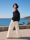 Woman in the Essential Heavyweight Stand Collar Jacket in Black on a granite sea terrace in Sardinia in the morning