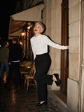 Woman in the Essential Non-Shrink Mock Neck Sweatshirt in White with black wide trousers, kicking up a heel outside a Paris café at 2am
