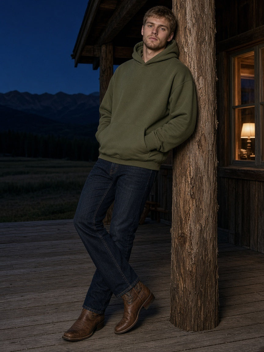 Man in the Essential Oversized Hoodie in Army Green leaning on the porch of a ranch lodge in Montana at night