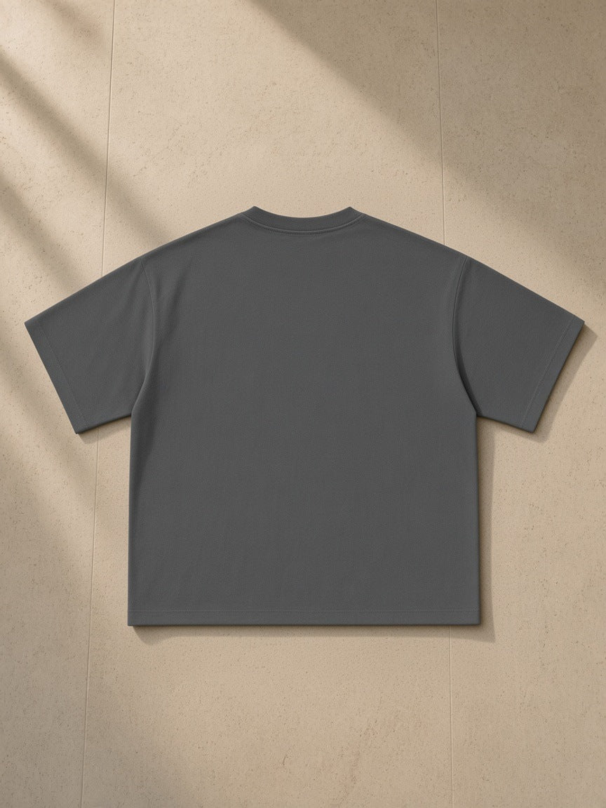 Essential Sorona Boxy T-Shirt in Charcoal, laid flat on pale limestone, back view