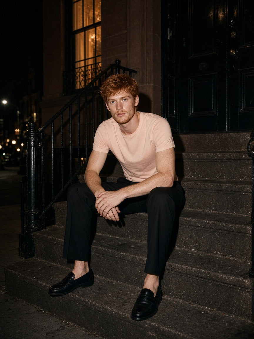 Man in the Marcel Afters Essential Standard Shoulder T-Shirt in Mild Apricot on a brownstone stoop in the West Village, New York at night