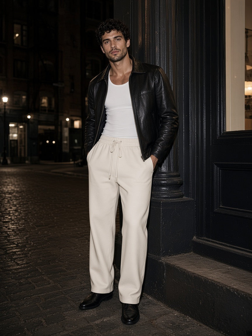 Man in the Essential Straight-Leg Sweatpants in White leaning on a cast-iron column in SoHo, New York at night