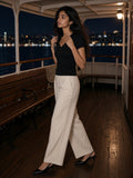 Woman in the Essential V-Neck Bodycon T-Shirt in Black on the rear deck of a night ferry across dark water