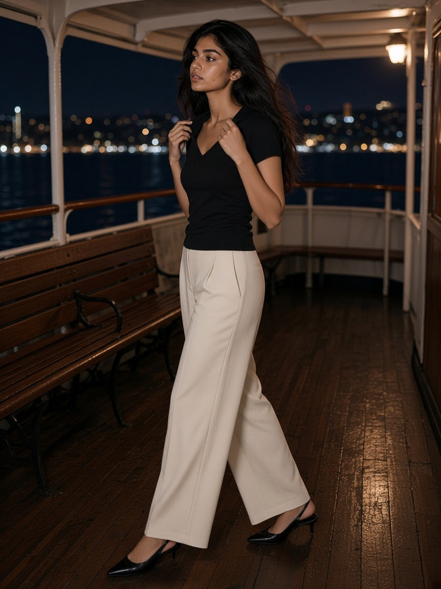 Woman in the Essential V-Neck Bodycon T-Shirt in Black on the rear deck of a night ferry across dark water