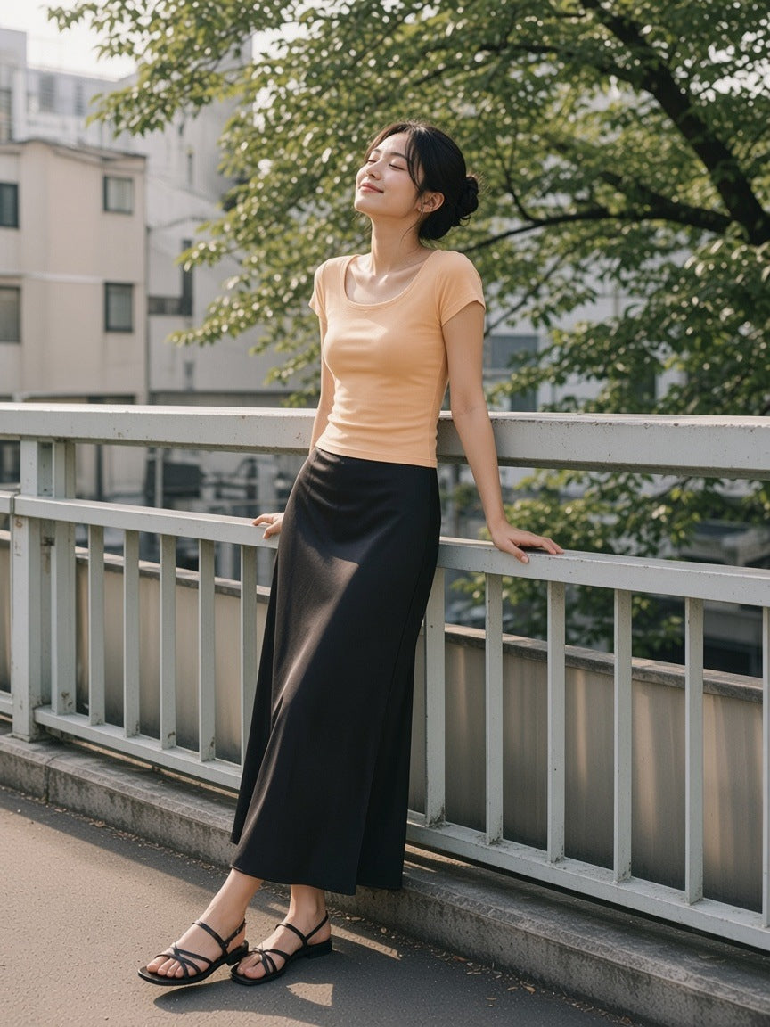 Woman in the Essential Wide Neck Baby T-Shirt in Light Apricot leaning on a footbridge rail in Aoyama, Tokyo in the morning