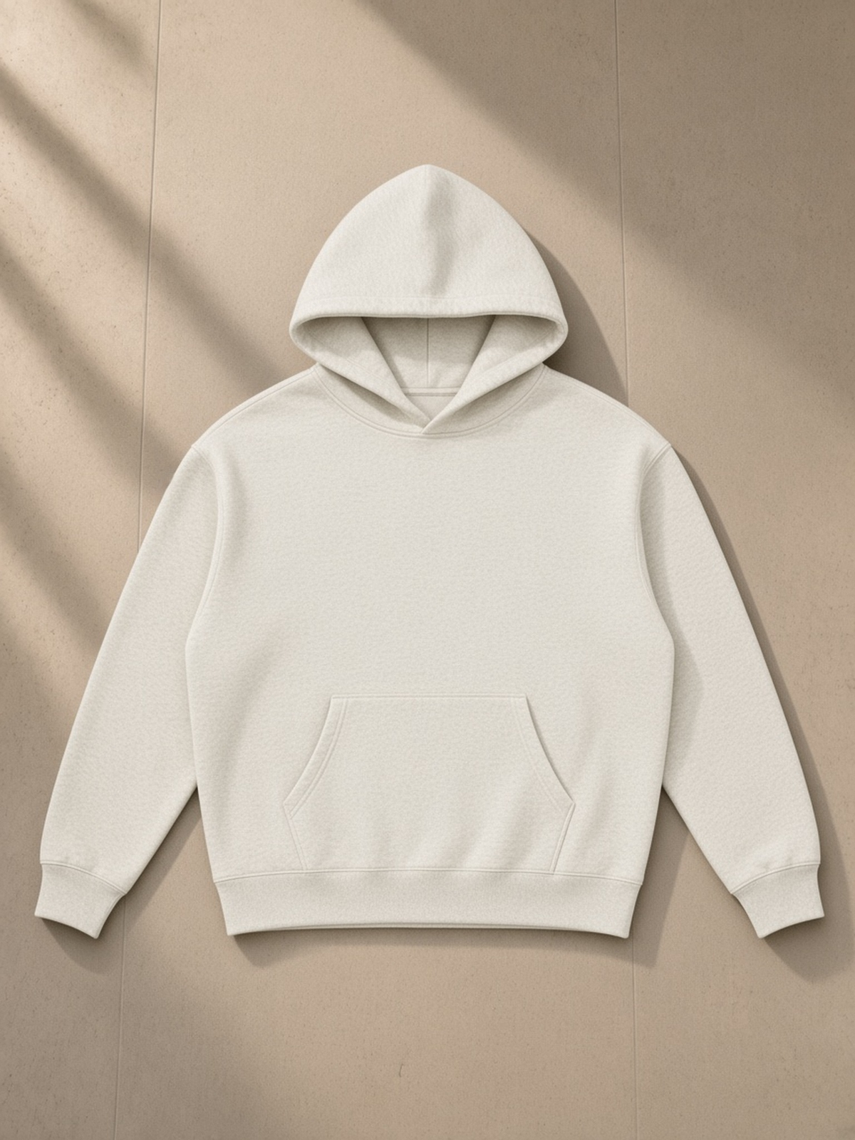 Oversize fleeced hoodie in Oat Gray, laid flat on pale limestone