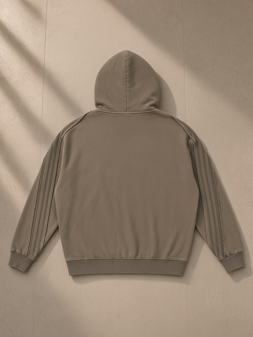 Unisex snow washed tape raw edge zip hoodie in Khaki, laid flat on pale limestone, back view