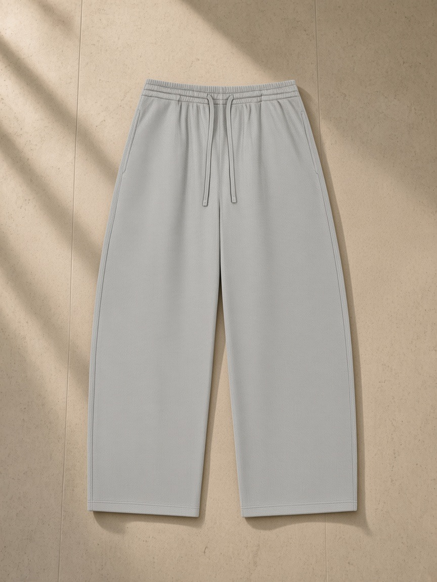Waffle barrel leg pants in Light Gray, laid flat on pale limestone