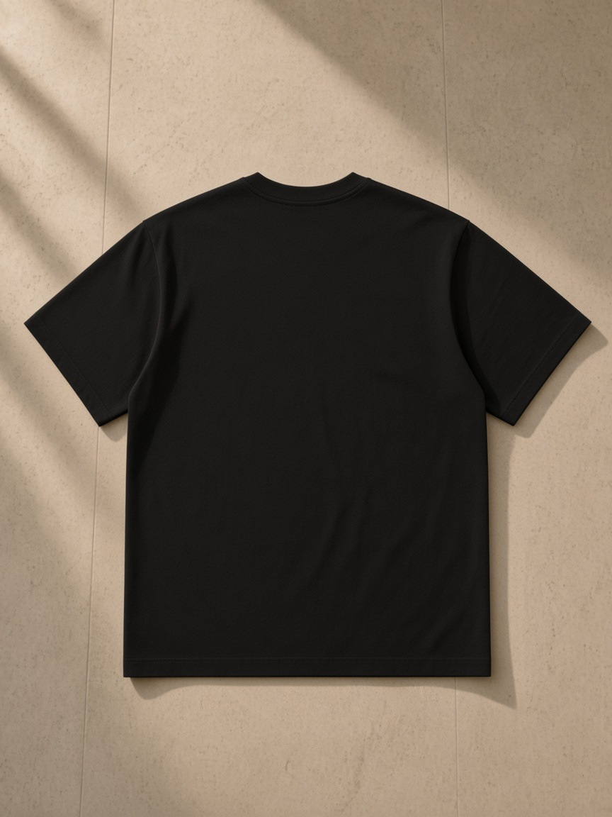 Solid Color Regular Fit T-Shirt in Black, laid flat on pale limestone, back.