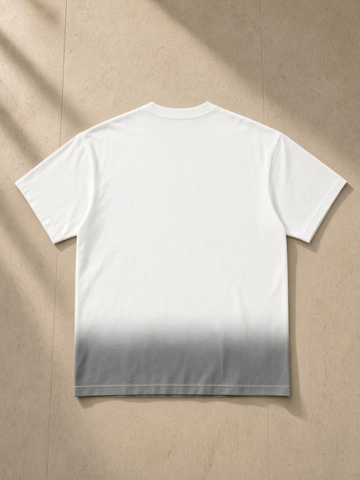 Sunfade Vintage Washed T-Shirt in White, laid flat on pale limestone, back.