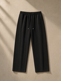 Unisex heavyweight sweatpants in Black, laid flat on pale limestone