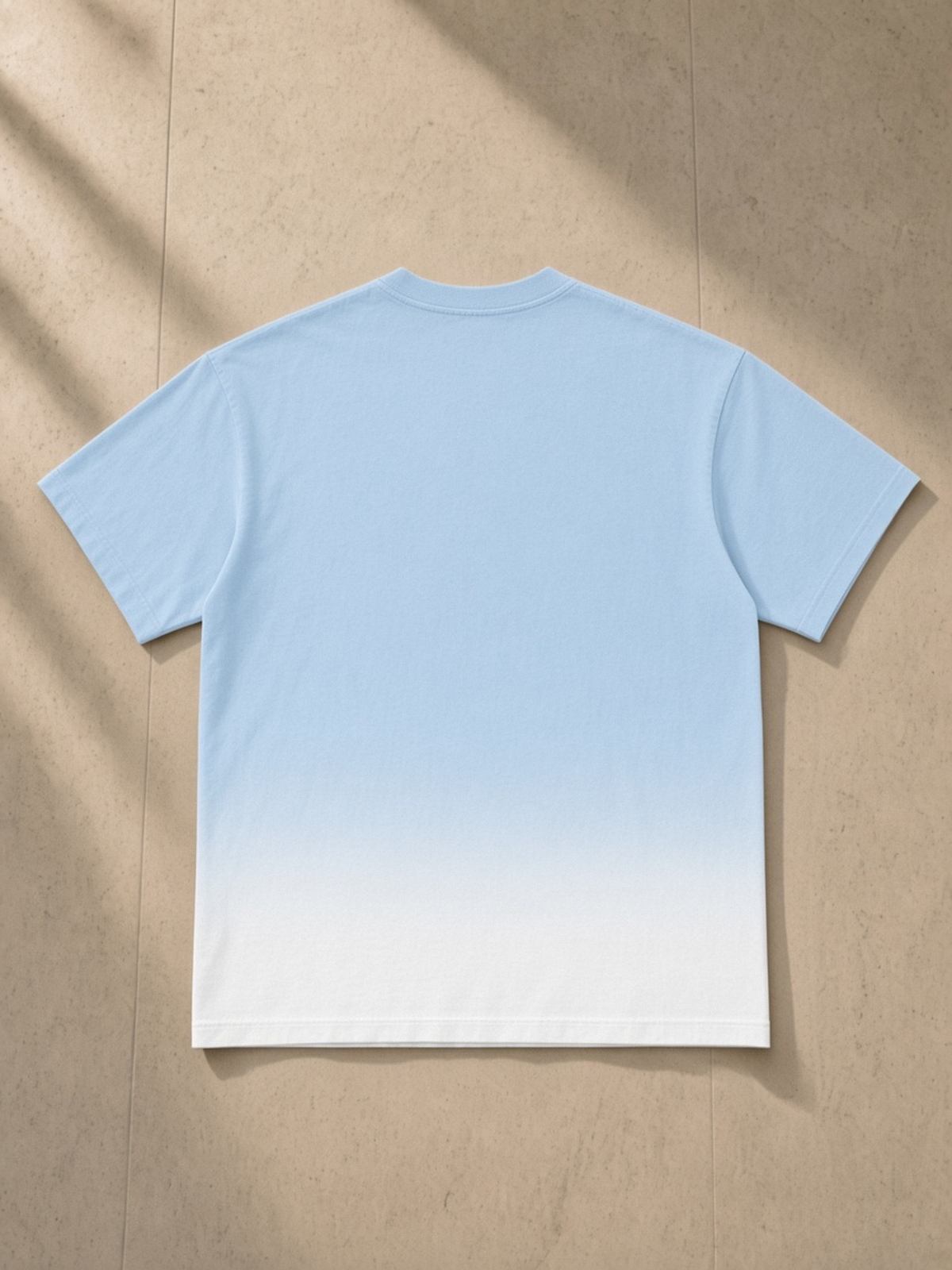 Sunfade Vintage Washed T-Shirt in Blue, laid flat on pale limestone, back.