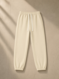 Essential fleece sweatpants in Apricot, laid flat on pale limestone