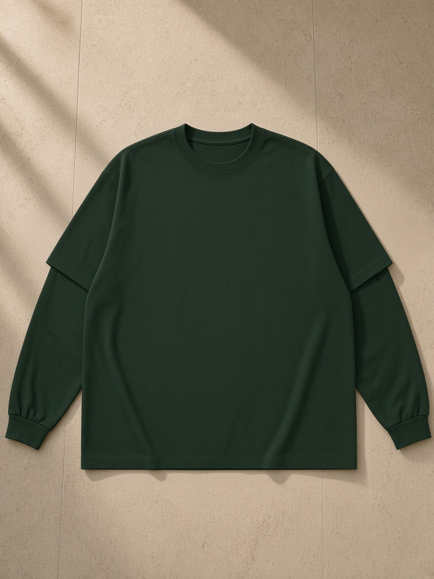 Layered oversized t-shirt in Dark Green, laid flat on pale limestone