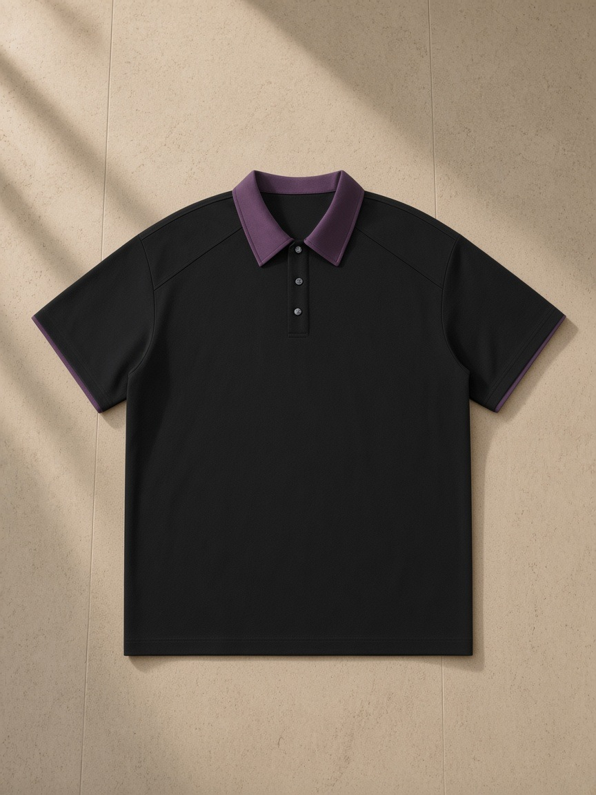 Contrast Collar Raglan Polo Shirt in Black, laid flat on pale limestone