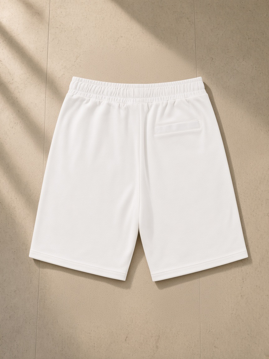 Essential Cotton Shorts in White, laid flat on pale limestone, back view