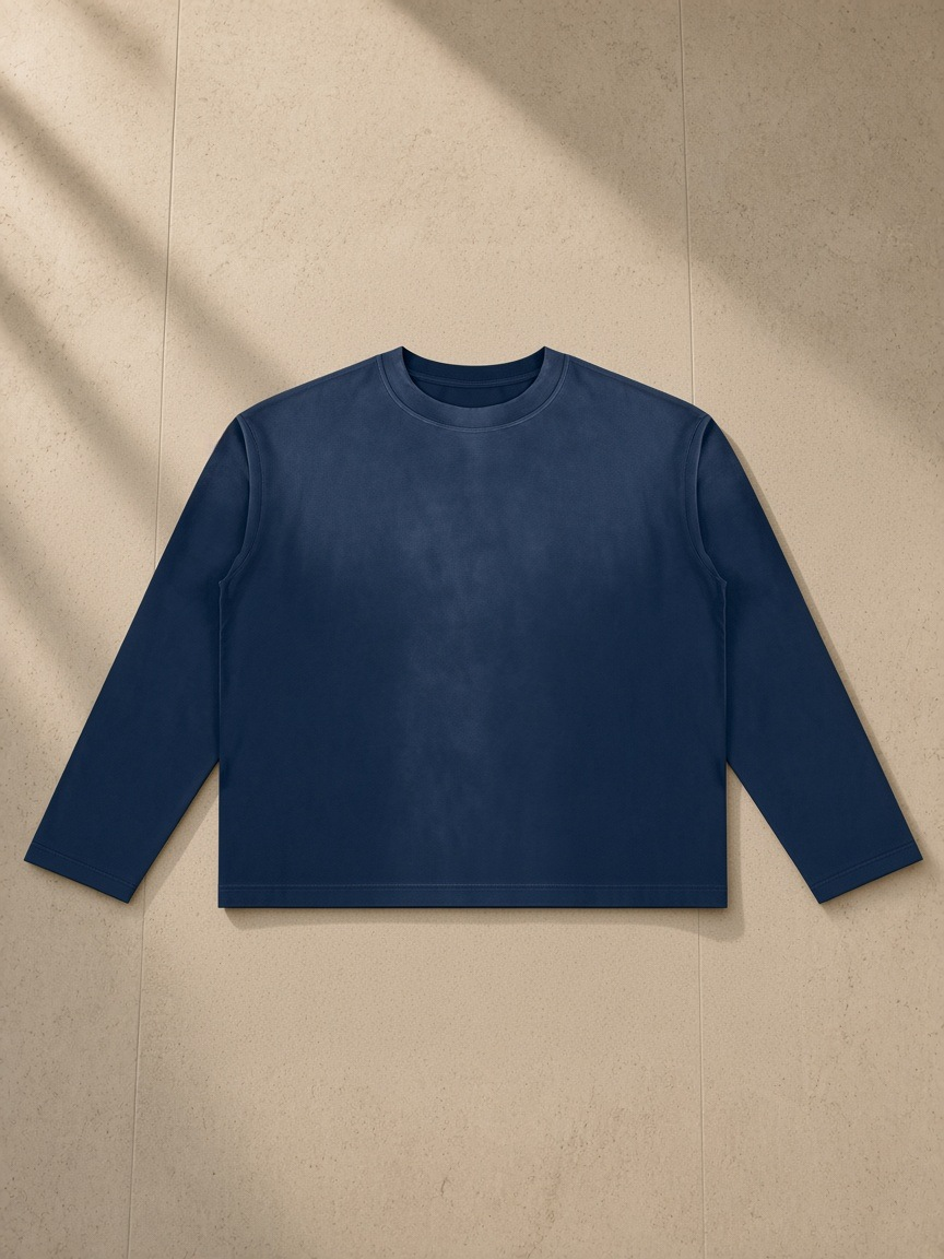 Sunfade boxy long sleeve t-shirt in Navy Blue, laid flat on pale limestone