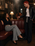 Two people in the Flared Sweatpants in Gray and Black, one seated in a leather booth and one setting down a glass, in a jazz club at night