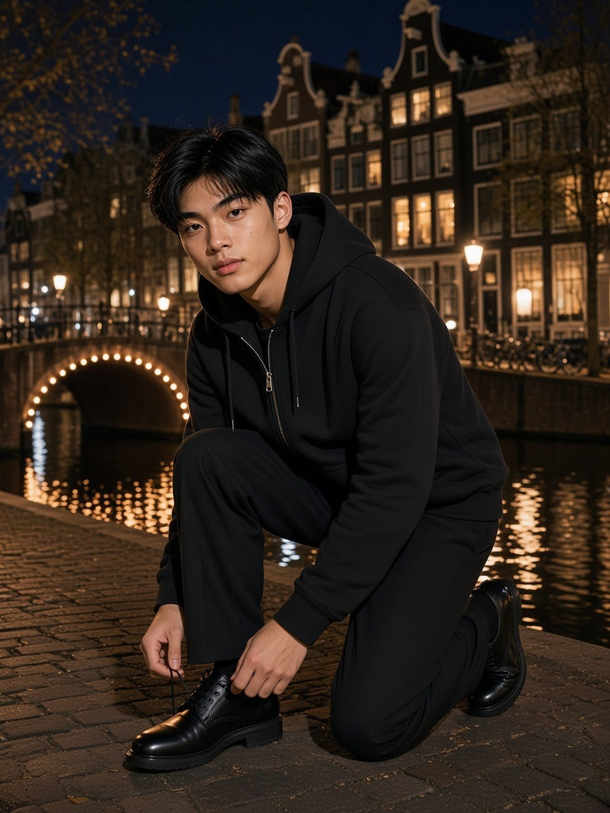 Man in the Marcel Afters Fleece Zip-Up Boxy Hoodie in Black on a canal bank in Amsterdam at night