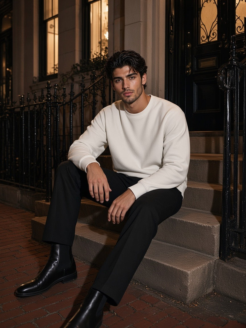 Man in the Fleeced Sweatshirt in White with black trousers and Chelsea boots, on townhouse steps in the West Village, New York at night
