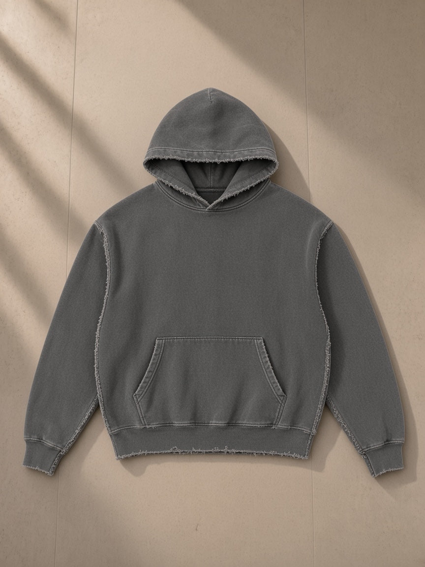 Frayed Enzyme Washed Fleece Hoodie in Dark Gray, laid flat on pale limestone, front view