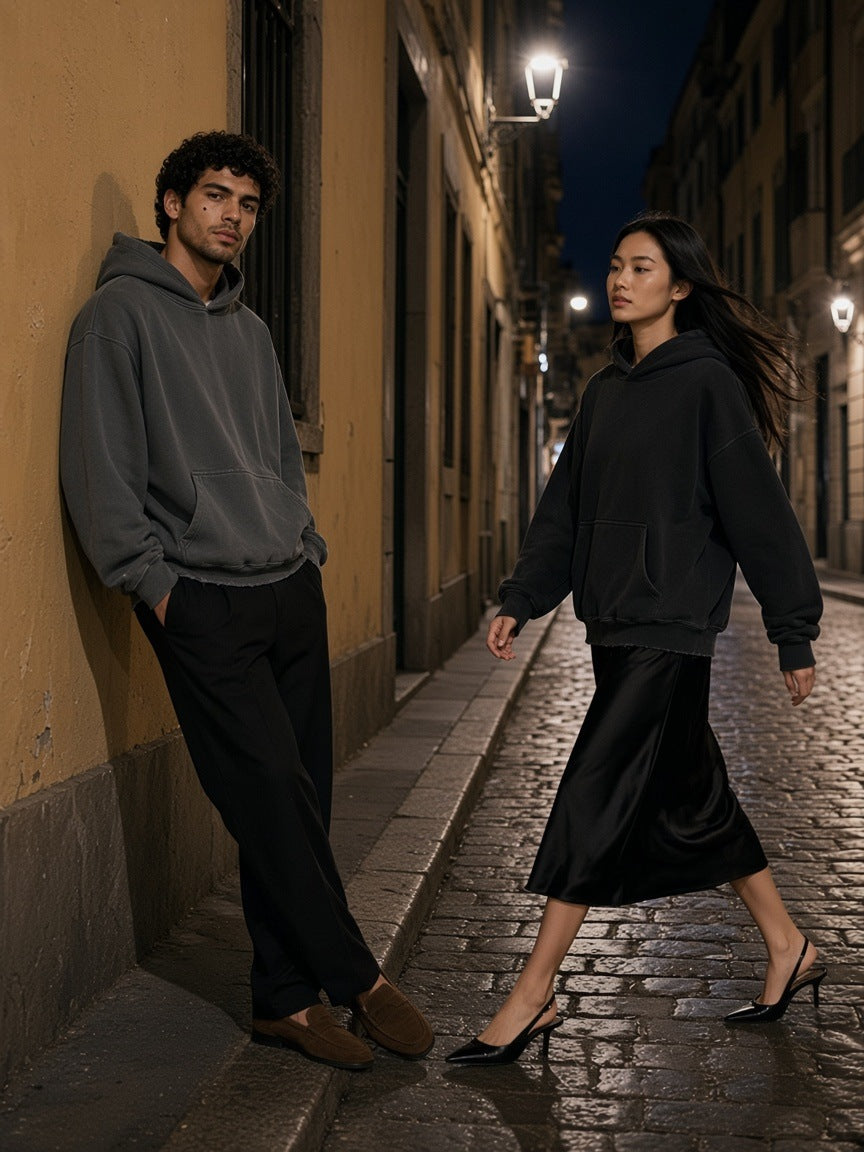 Two people in the Frayed Enzyme Washed Fleece Hoodie in Dark Gray and Black on a Brera side street in Milan at night