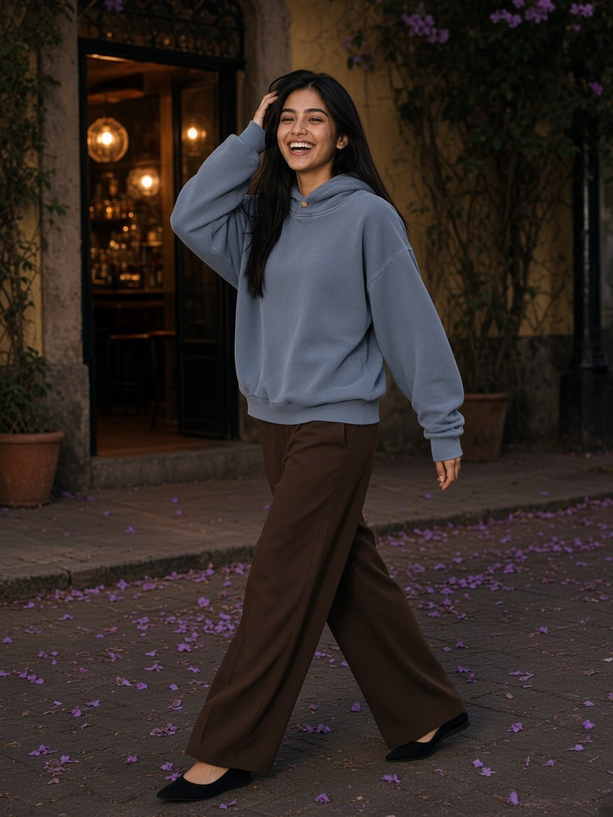 Woman in the Frayed Enzyme Washed Fleece Hoodie in Blue with brown wide trousers, walking a jacaranda street in Colonia Roma, Mexico City at night