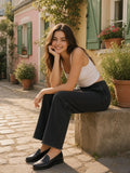 Woman in the Frayed Enzyme Washed Fleece Sweatpants in Black sitting on a stone planter on a pastel Paris street