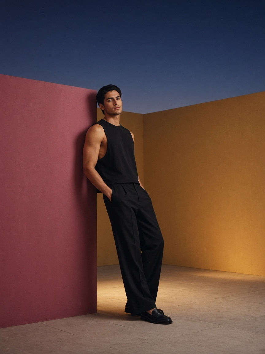 Man in the French Terry Boxy Tank Top in Black in a rose-pink hotel courtyard in Mexico City at dusk