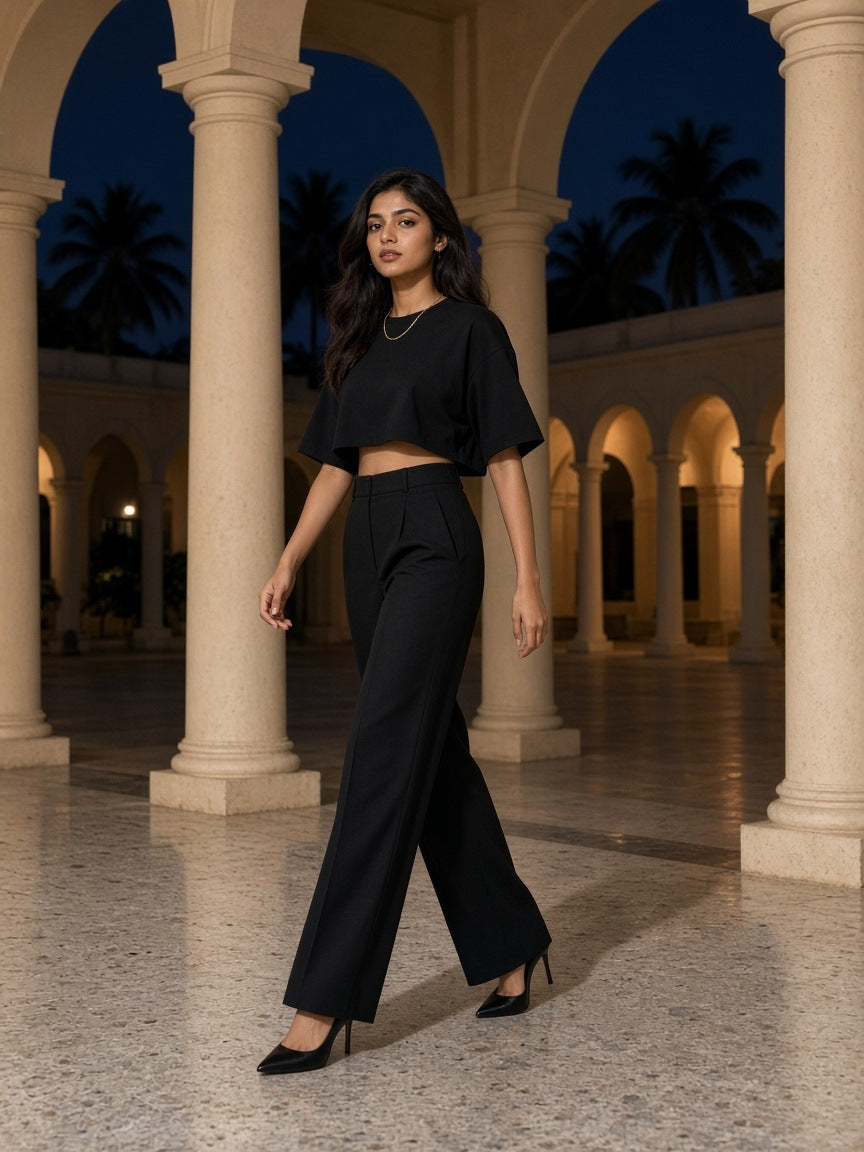 Woman in the Marcel Afters French Terry Raw Edge T-Shirt in Black in an Art Deco hotel colonnade in Mumbai at night