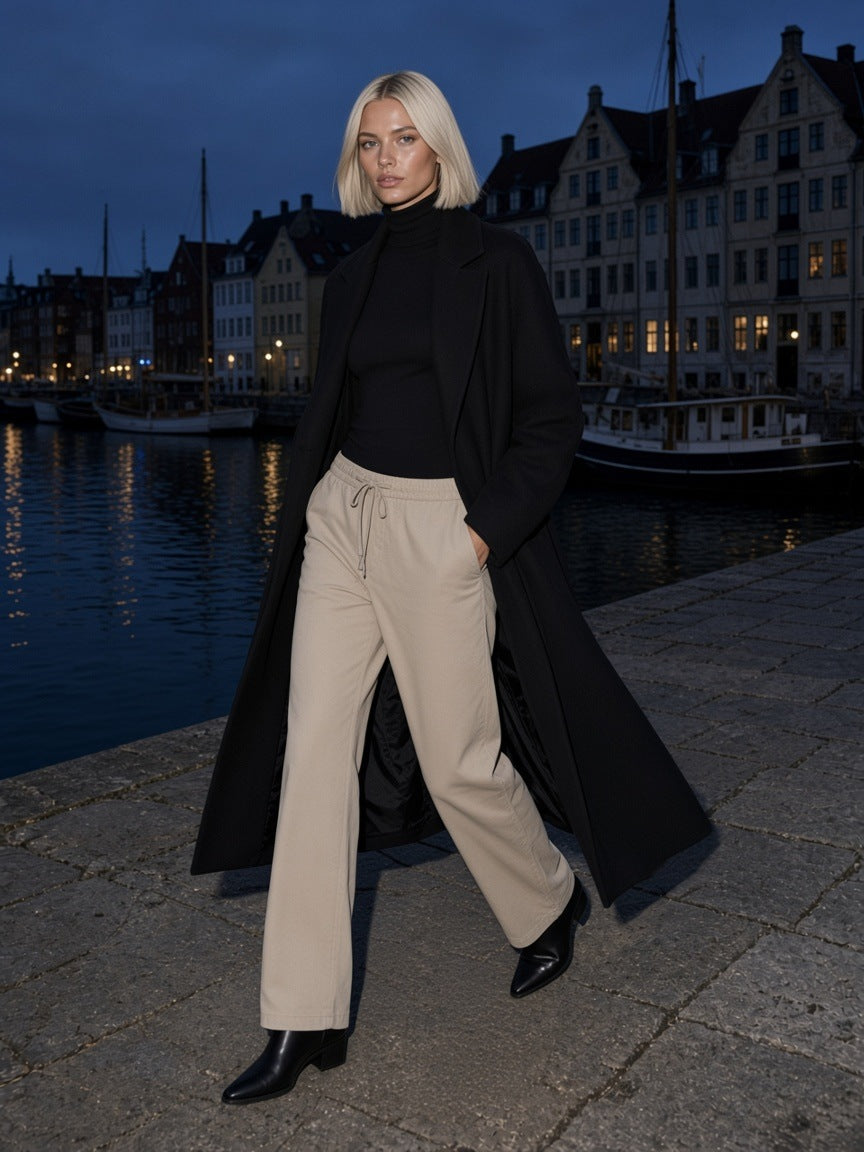 Woman in the Heavyweight Cotton Straight-Leg Pants in Pale Khaki walking a harbour quay in Copenhagen at night
