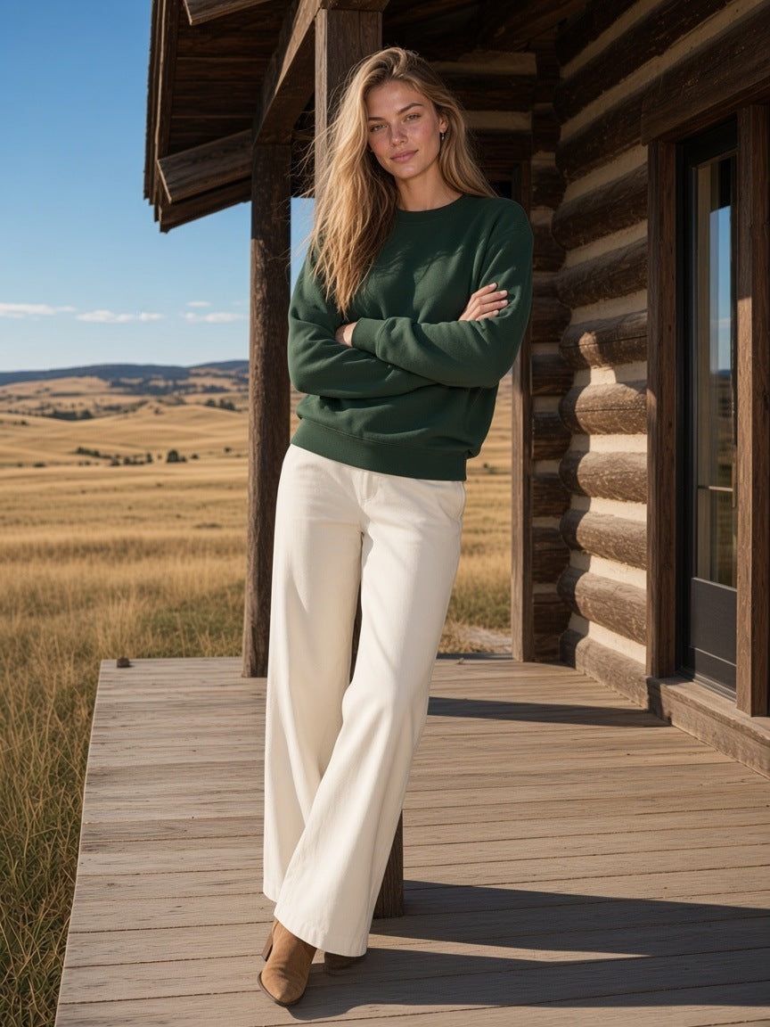 Woman in the heavyweight crewneck sweatshirt in Blackish Green standing on the porch of a ranch lodge in Montana by day
